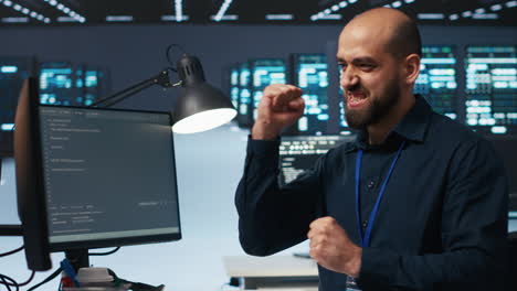 Cheerful-man-pleased-after-using-PC-to-fix-server-cabinets-errors-in-data-center