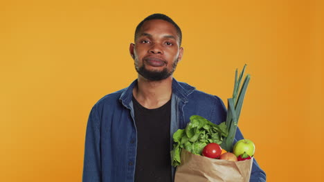Young-adult-showing-peace-sign-gesture-and-holding-organic-groceries