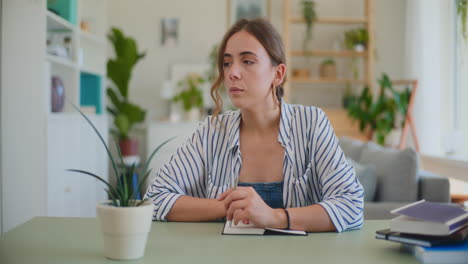 Vista-Frontal-De-Una-Estudiante-Aprendiendo-A-Escribir-Leyendo-En-El-Escritorio