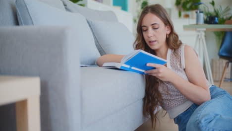 Frau-Konzentriert-Sich-Auf-Das-Lesen-Und-Lernen-Neben-Dem-Sofa-Auf-Dem-Boden