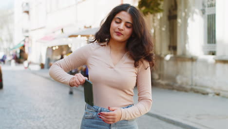 Mujer-India-Utiliza-Un-Teléfono-Inteligente-Móvil-Celebrando-Ganar-Buenas-Noticias-Al-Aire-Libre-En-Las-Calles-Urbanas-De-La-Ciudad