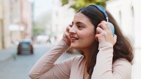 Feliz-Joven-India-Con-Auriculares-Inalámbricos-Escuchando-Música-Bailando-En-Las-Calles-De-La-Ciudad-Al-Aire-Libre