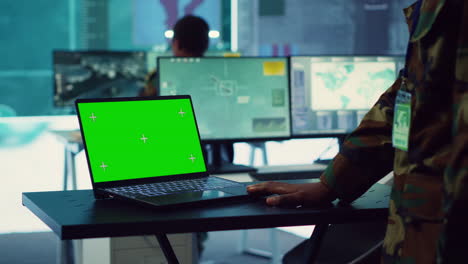 Commander-examines-a-greenscreen-on-laptop-in-military-command-center