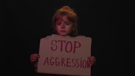Afraid-dirty-faced-homeless-poor-girl-showing-banner-with-inscription-massage-Stop-Aggression