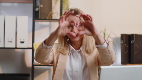 Young-business-woman-makes-symbol-of-love,-showing-heart-sign-to-camera,-express-romantic-feelings