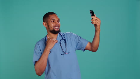 Male-nurse-using-mobile-phone-to-take-selfies-during-job-shift-break.