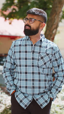 Happy-smiling-Indian-young-man-tourist-walking-in-urban-city-street-outdoors-in-summer-daytime