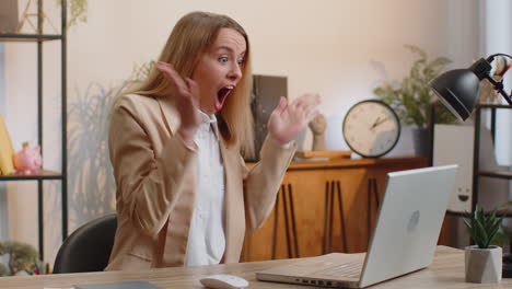 Businesswoman-winner-working-browsing-typing-on-laptop-at-office-celebrate-big-lottery-win-good-news