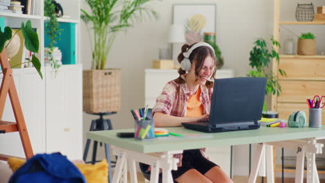 Cheerful-Teenage-Girl-Rejoices-and-Raises-Her-Hands-Up-in-a-Gesture-of-Victory-While-Playing-Games-on-the-Computer