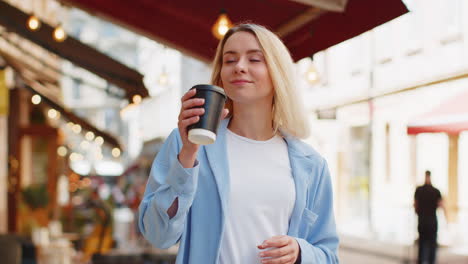 Happy-woman-enjoying-morning-coffee-hot-drink-and-smiling-relaxing,-taking-a-break-on-city-street