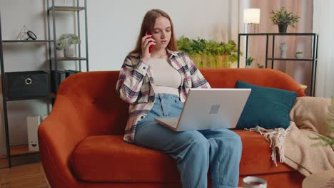 Young-woman-using-laptop-computer-sitting-on-sofa-working,-online-shopping-from-home-office