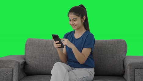 Happy-Indian-teenage-girl-scrolling-through-phone-Green-screen