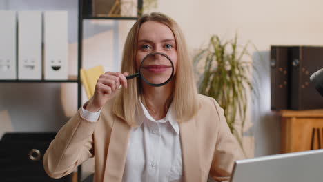 Businesswoman-holding-magnifier-glass-on-teeth,-looking-at-camera,-showing-funny-smiling-silly-face