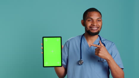 Portrait-of-male-nurse-showing-medical-instructions-video-on-green-screen-tablet