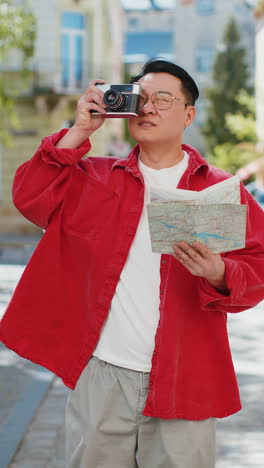 Asian-man-tourist-traveling-on-weekends-exploring-town-looking-city-map,-making-photo-pictures