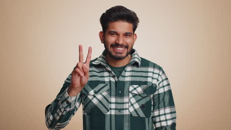 Young-indian-man-showing-victory-sign,-hoping-for-success-and-win,-doing-peace-gesture,-smiling