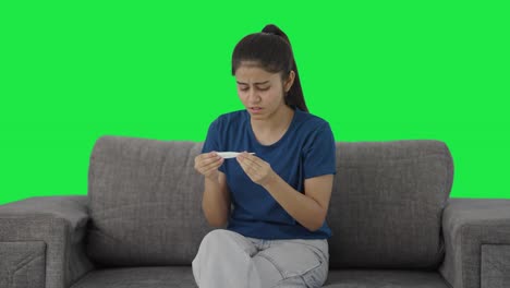 Sick-Indian-teenage-girl-checking-fever-using-thermometer-Green-screen