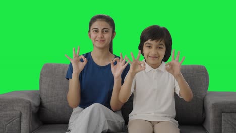 Happy-Indian-siblings-showing-okay-sign-to-the-camera-Green-screen