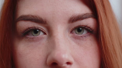 Close-up-macro-portrait-of-young-woman-face-smiling,-redhead-girl-eyes-looking-at-camera-blink-wink