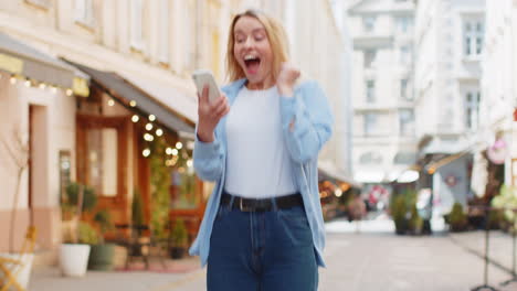 Mujer-Feliz-Usando-Un-Teléfono-Inteligente-Móvil-Celebrando-Ganar-Buen-Mensaje-Noticias-Lotería-Casino-Victoria-Del-Premio-Mayor