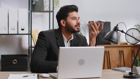 Indian-business-man-working,-having-mobile-phone-talk-at-office-workplace-using-messenger-chat-apps