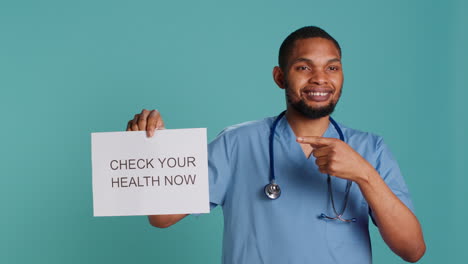 Portrait-of-male-nurse-holding-sign-urging-people-to-do-medical-appointments