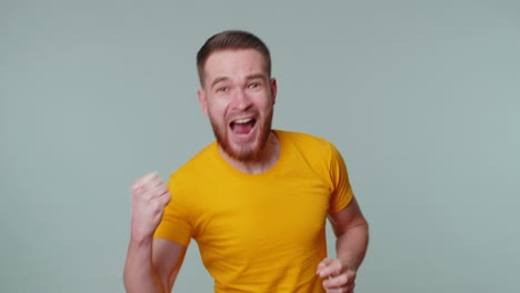 Stylish-man-in-t-shirt-shouting,-raising-fists-in-gesture-I-did-it,-celebrating-success,-winning