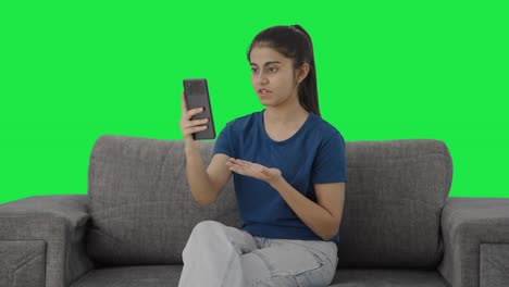 Serious-Indian-teenage-girl-talking-on-video-call-Green-screen