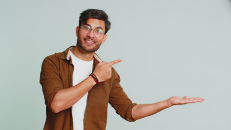 Young-man-showing-thumbs-up-and-pointing-at-right-on-blank-space-place-for-your-advertisement-logo