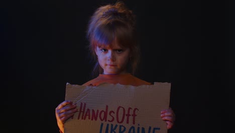 Upset-homeless-girl-kid-protesting-war-conflict-raises-banner-with-inscription-Hands-Off-Ukraine