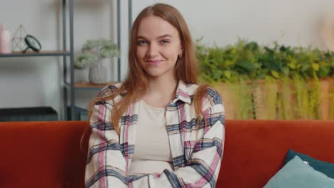 Portrait-of-happy-one-beautiful-teenager-student-girl-smiling,-looking-at-camera-at-home-on-sofa