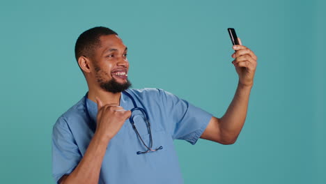 Male-nurse-using-mobile-phone-to-take-selfies-during-job-shift-break.