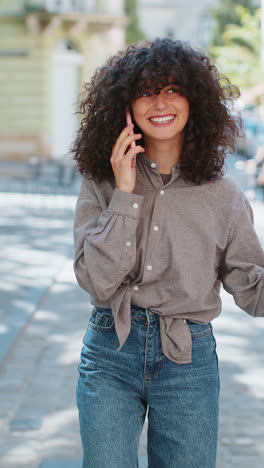 Mujer-Sonriente-Feliz-Teniendo-Una-Conversación-Remota-Hablando-Por-Teléfono-Inteligente-Chismes-De-Buenas-Noticias-En-Las-Calles-De-La-Ciudad