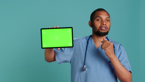 Cheerful-nurse-showing-medical-instructions-video-on-chroma-key-tablet