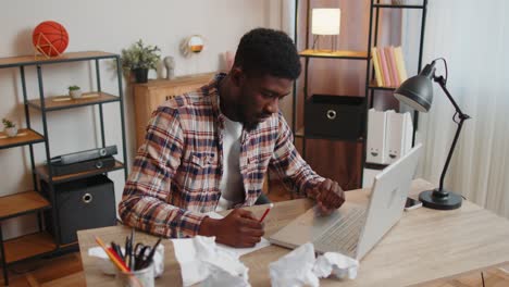 Tired-man-at-home-office-falling-asleep-on-table-with-laptop-computer,-crumpled-sheets-of-paper