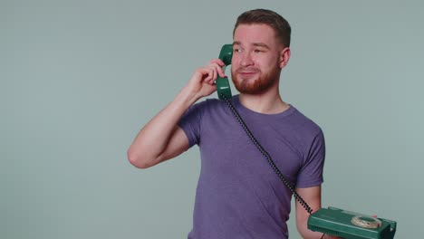 Cheerful-tourist-man-secretary-talking-on-wired-vintage-telephone-of-80s,-says-hey-you-call-me-back