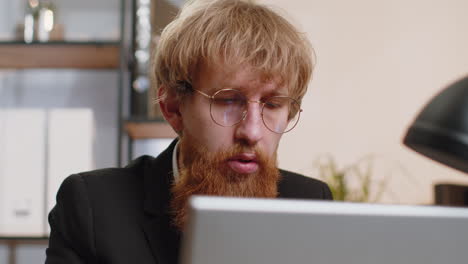 Close-up-businessman-freelancer-at-office-workplace-working-on-laptop-computer-sends-online-messages