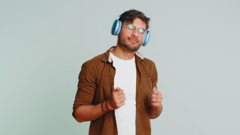 Happy-funny-Indian-man-in-headphones-listening-music-dancing-disco-having-fun-relaxing-on-party