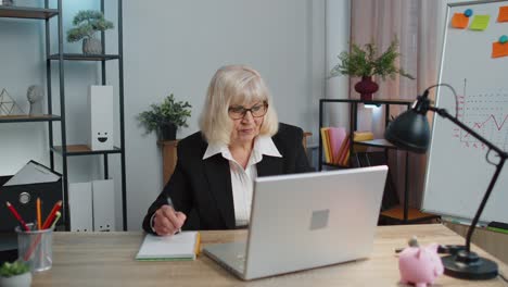 Mujer-Mayor-Madura-De-Oficina-De-Negocios-Aprendiendo-En-Línea-Escribiendo-Notas-Desde-Una-Computadora-Portátil,-Seminario-Web-En-Vivo