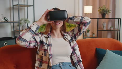 Una-Mujer-Joven-Usa-Gafas-De-Realidad-Virtual-En-Casa,-Disfrutando-Del-Concepto-De-Vídeo-Moviendo-Las-Manos-En-El-Aire