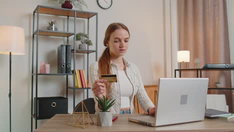 Woman-sitting-at-home-using-credit-bank-card-and-laptop-pc-while-transferring-money-online-shopping