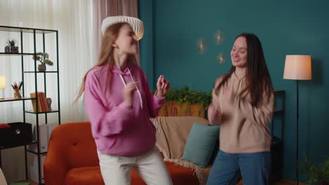 Happy-two-teenage-girls-siblings-or-bloggers-couple-dancing-at-home-having-fun-enjoying-trendy-dance