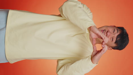 Smiling-chinese-man-makes-heart-gesture-demonstrates-love-sign-expresses-good-feelings-and-sympathy