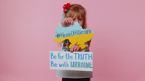 Toddler-Ukrainian-girl-alone-protesting-war-conflict-raises-inscription-massage-Hands-Off-Ukraine