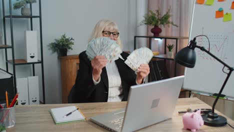 Contable-De-Mujer-De-Negocios-Celebrando-El-éxito-Empresarial-Bailando-Con-Una-Pila-De-Dinero-En-Efectivo-En-Dólares