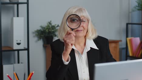 Senior-business-woman-looks-through-a-magnifying-glass,-investigate,-examine,-analyzing,-reading