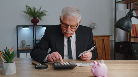 Senior-business-office-man-accountant-or-banker-using-calculator-making-money-cash-calculations