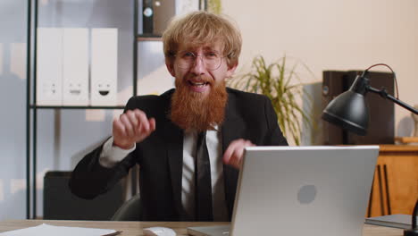 Business-man-working-on-office-laptop-pointing-to-camera-looking-with-happy-expression-making-choice