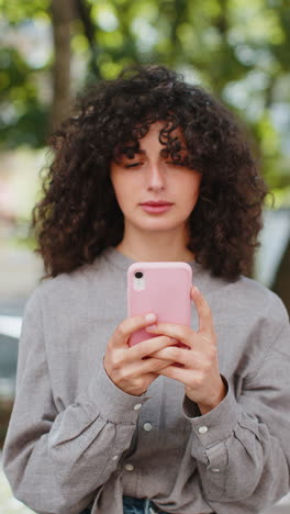 Excited-happy-Caucasian-young-woman-use-smartphone-celebrating-win-good-message-news-in-city-street