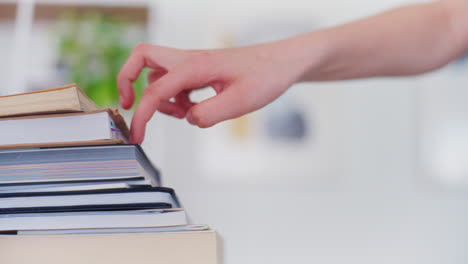 Hands-of-a-Young-Student-Climbing-Books,-a-Symbol-of-Education-and-Climbing-the-Career-Ladder